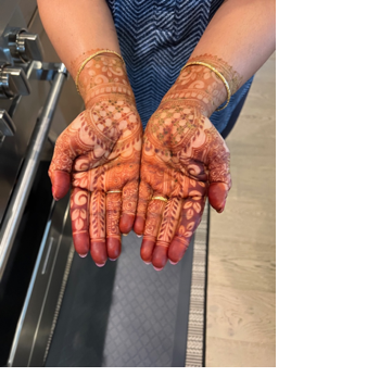 A person's hands with henna designs

Description automatically generated